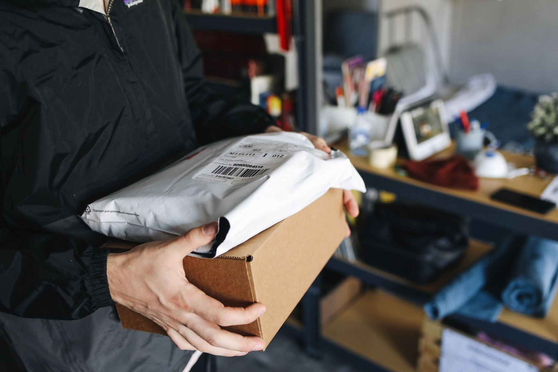 Close-up of hands holding cardboard and plastic packages, symbolizing delivery and shipping.